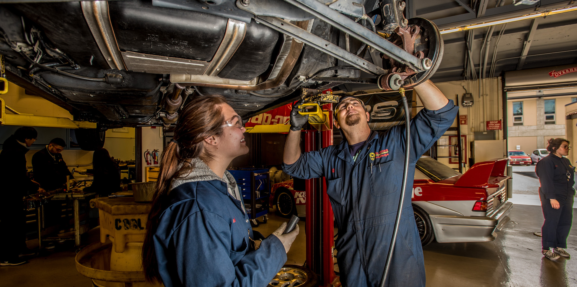 two students working under car