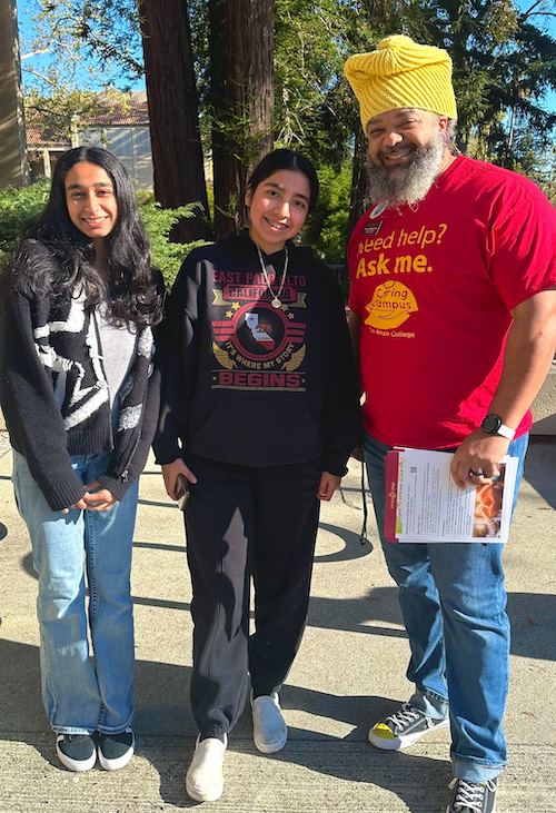 male staffer with yellow hat standing with two female students