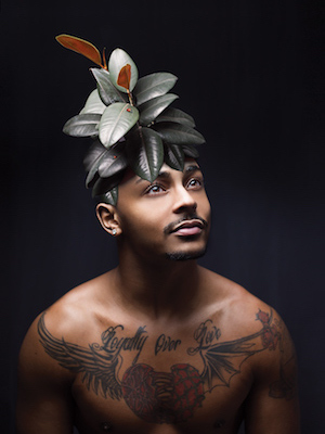 tattooed man with bare chest and leafy headdress