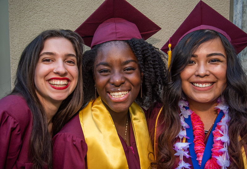 three smiling young women in grad gear