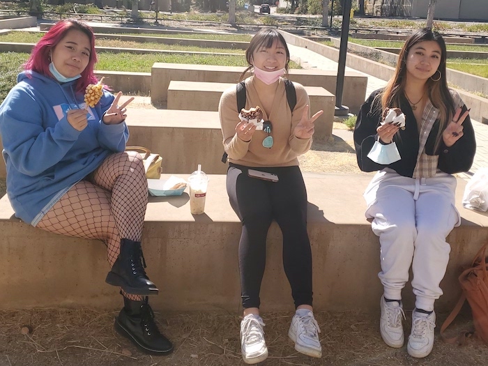 three young women eating a snack outside