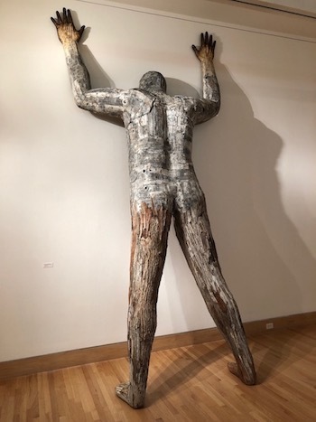 sculpture of man pushing against wall