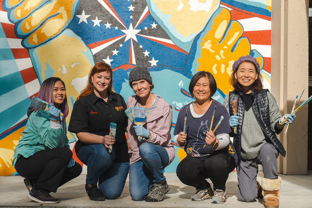 students and instructor kneeling in front of mural