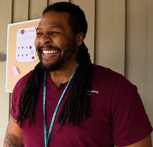 Smiling man with long hair and red shirt