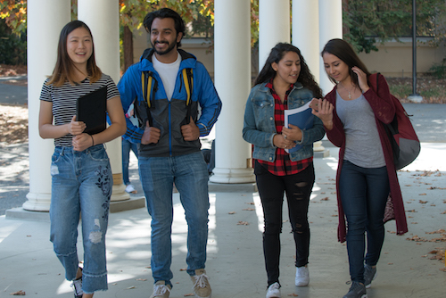 students walking past white columns