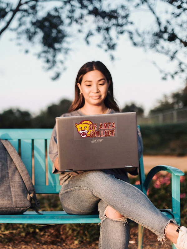 young woman on bench with laptop