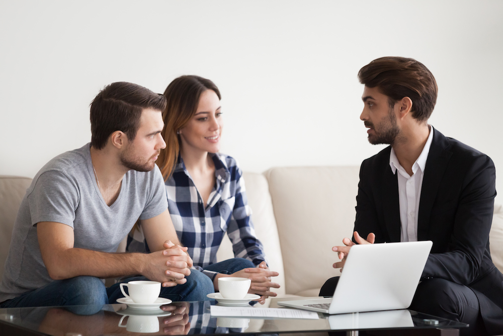 young man in suit speaking with man and woman