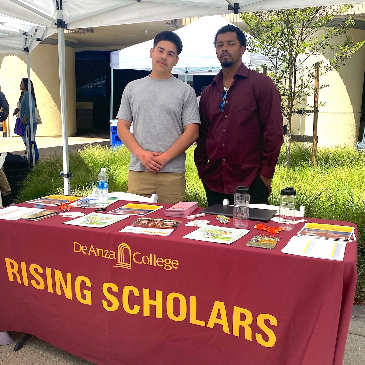 two students standing at Rising Scholars information table