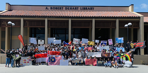 students pose for group photo in front of library