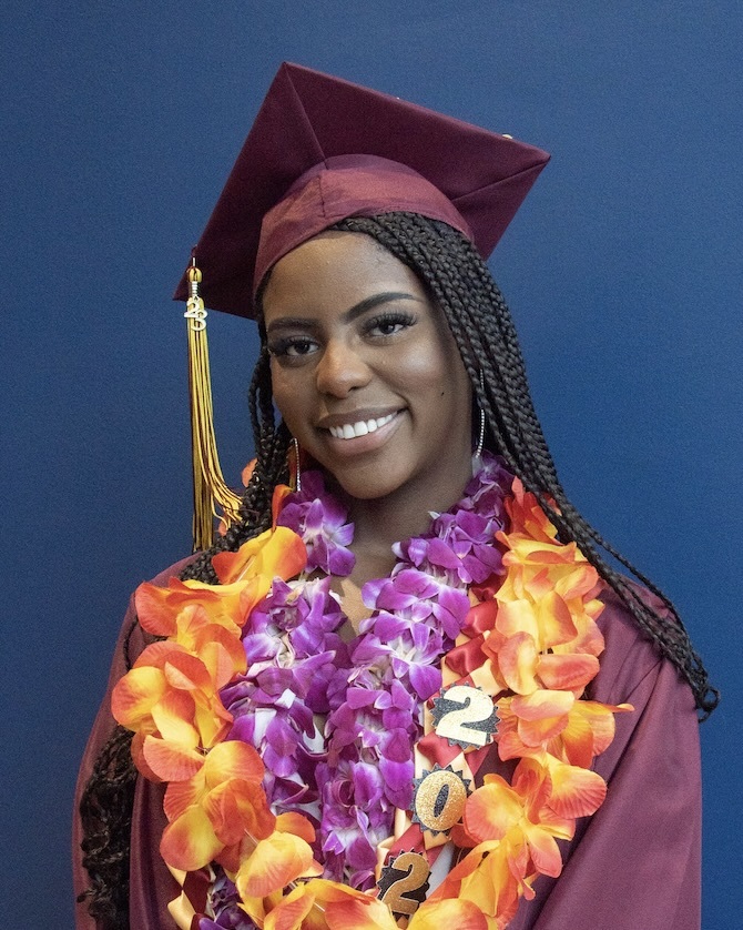 smiling young woman in cap and gown with flower leis