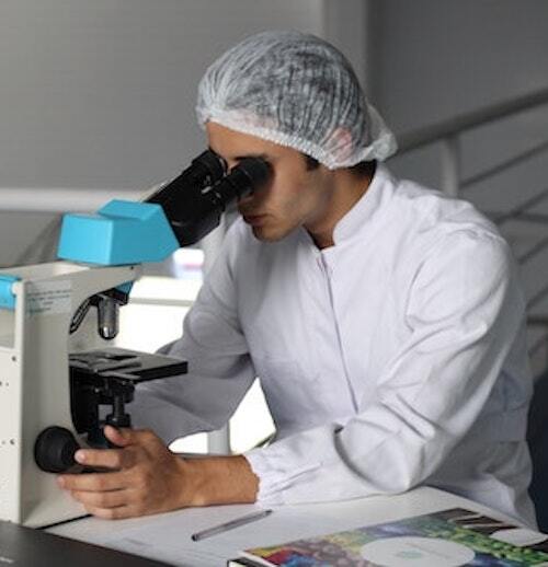 young man in lab coat looking in microscope