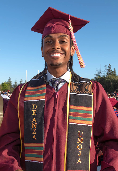 smiling male grad in cap, gown and Umoja sash