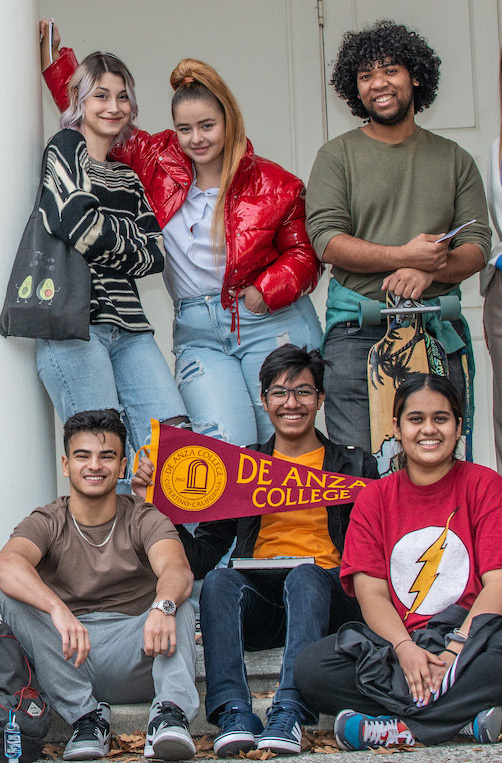 group of smiling students with De Anza pennant