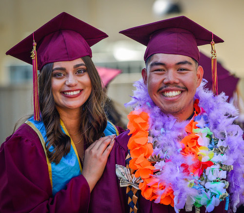 smiling young woman and young man in grad regalia