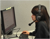 Female working on a computer wearing a headset.