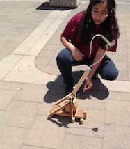 Female student launching her and her partners trebuchet.