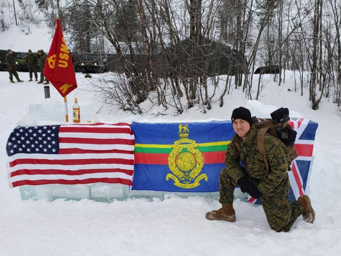 William Lai in military gear kneeling next to flags in snowy woods